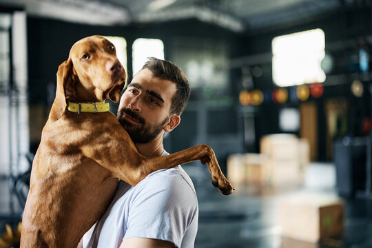 Athletic man with his dog after sports training at pet friendly gym.