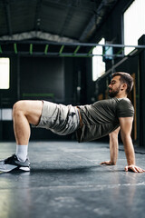 Fototapeta na wymiar Athletic man doing reverse plank bridge exercise while working out in gym.