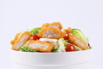 Mixed Vegetable Salad with Breaded Fish Fillet in a bowl. Healthy green salad with battered fish fillet and vegetables isolated on white background. Fish fillet. Healthy food. Hydroponics vegetable