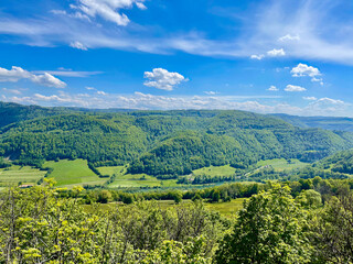 Obraz premium Panorama from the Swiss village of Réclère over the Doubs valley, its mountains and its forests, on a sunny summer day