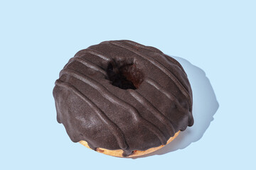 brown donut with glaze on blue pastel background