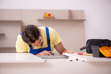 Young male carpenter repairing table at home