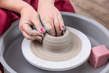 Close up of female potter hands shaping handcraft crockery in studio.