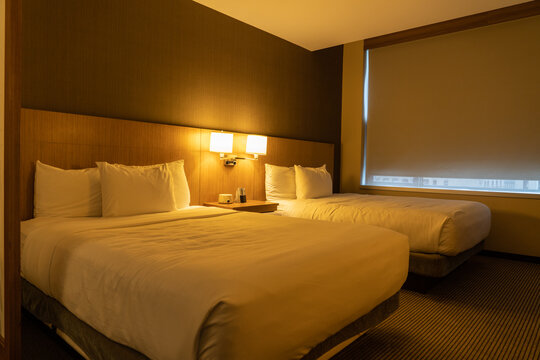Standard two queen size beds hotel room in dim yellow light
