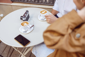 Close-up of man and lady sitting at table with cups of coffee