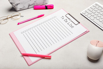 Clipboard with blank to do list, stationery supplies, eyeglasses, computer mouse and keyboard on...