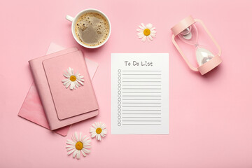 Blank to do list, notebook, cup of coffee, hourglass and chamomile flowers on color background