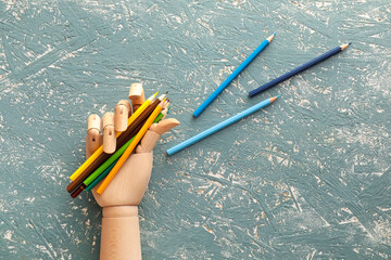 Wooden hand with colorful pencils on grunge background