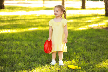 Cute little girl playing frisbee in park