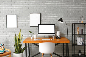 Interior of room with modern workplace near grey brick wall