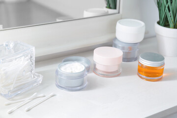 Fototapeta na wymiar Jars of cosmetic cream on dressing table in room, closeup