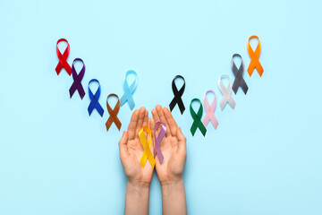Female hands with different awareness ribbons on color background. World Cancer Day