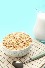 Bowl of raw oatmeal and spoon on color background