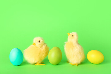 Cute yellow chickens and Easter eggs on green background