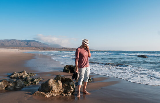 mature man talking on the cell phone on the beach at sunset