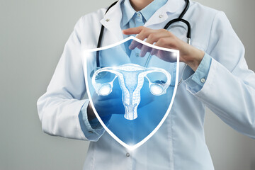 Unrecognizable female doctor holding shield and graphic virtual visualization of Uterus organ in...