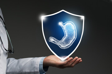 Unrecognizable female doctor holding shield and graphic virtual visualization of Stomach organ in...