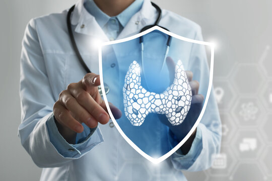 Unrecognizable female doctor holding shield and graphic virtual visualization of Thyroid Gland organ in hands.