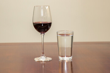 red wine in the glass and water in the cup on the wooden table. Wine and water