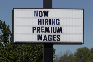 Now Hiring Premium Wages sign. Amid a nationwide shortage of workers, companies, businesses and restaurants are increasing wages to attract applicants.