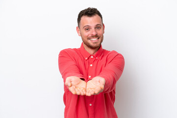 Young Brazilian man isolated on white background holding copyspace imaginary on the palm to insert...
