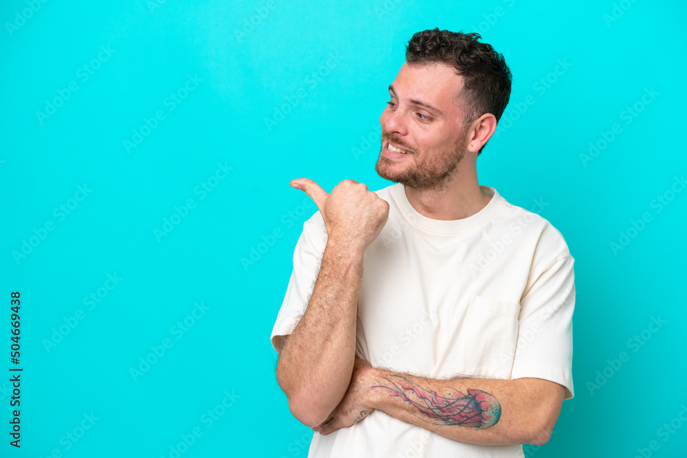 Poster young brazilian man isolated on blue background pointing to the side to present a product