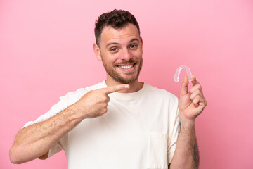 Brazilian man holding invisible braces and pointing it - obrazy, fototapety, plakaty
