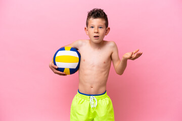 Little caucasian boy playing volleyball isolated on pink background with shocked facial expression
