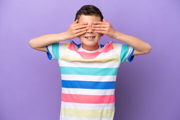 Little boy isolated on purple background covering eyes by hands and smiling