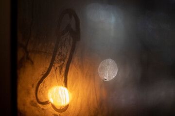 Drawing on wet glass. Foggy window. Warm light is reflected in surface of glass.