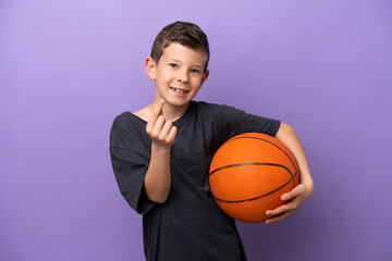 Little boy playing basketball isolated on purple background making money gesture