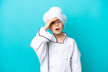 Little chef boy isolated on blue background doing surprise gesture while looking to the side