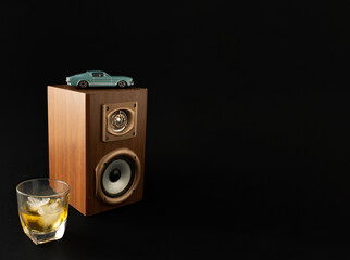 Old school classy composition, with blue oldtimer, wooden speakers and cold drink beverages. Classy, vintage concept on black background.
