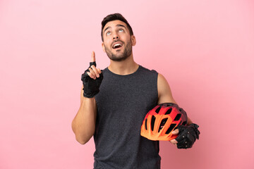Young cyclist man isolated on pink background pointing up a great idea - obrazy, fototapety, plakaty