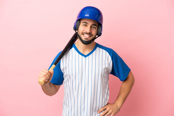 Baseball player with helmet and bat isolated on pink background posing with arms at hip and smiling