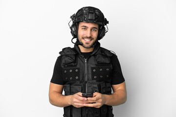 Young caucasian swat isolated on white background sending a message with the mobile