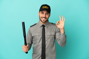 Young security man isolated on blue background showing ok sign with fingers