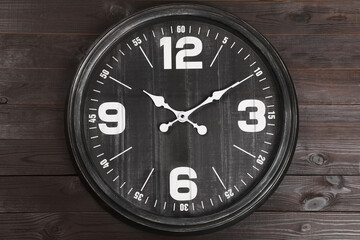 Stylish analog clock hanging on wooden wall