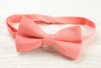 Stylish pink bow tie on white wooden background, closeup