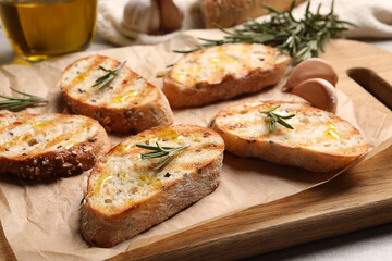 Tasty bruschettas with oil and rosemary on wooden board, closeup