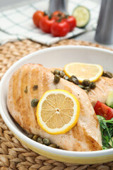 Delicious cooked chicken fillets with capers and salad on table, closeup