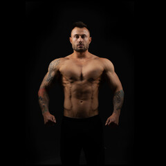 Fototapeta na wymiar Muscular male bodybuilder with a naked toros on a black background.