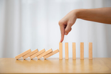 Hand stopping falling dominos to prevent a total collapse and establish stability. leadership and...
