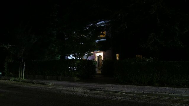 Car slowly passing large stand alone house at night