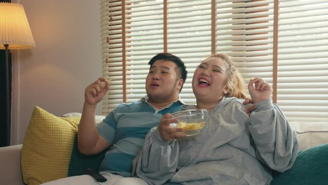 Fat Asian couple having fun to watch online live concerts on TV