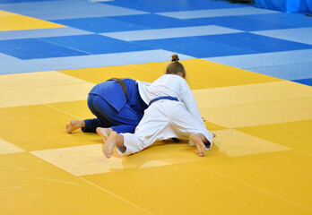 Two female judoists in kimonos compete on the tatami