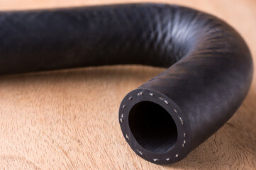 automotive hose, fluid carrying engine hose made of reinforced synthetic rubber on a wooden table...