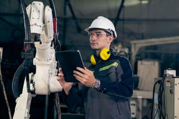 Young factory worker working with adept robotic arm in a workshop . Industry robot programming...