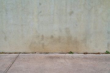 urban texture and background old gray grunge building wall and concrete pavement with some green...