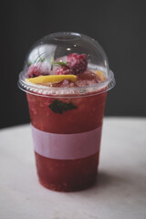 Cold pink non-alcohol cocktail with raspberry, lime, mint and ice cubes